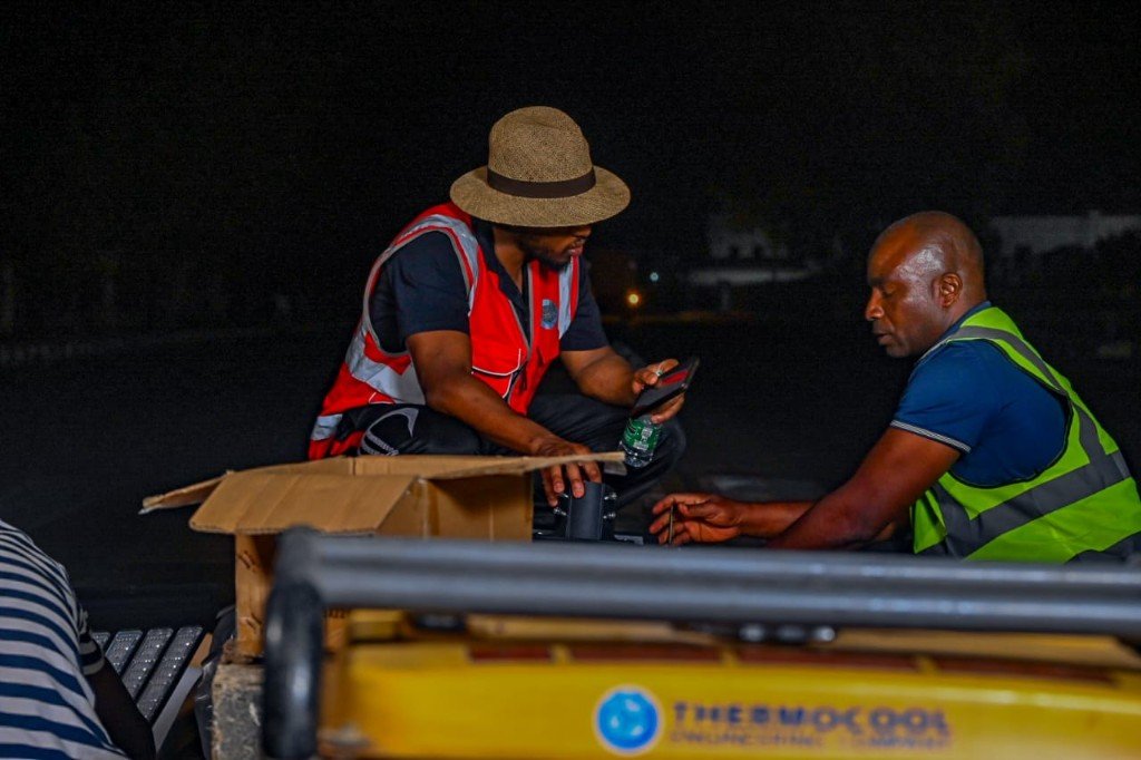 A supervisor briefing a local technician on a tablet beside the works vehicle